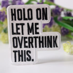Puede incluir: Parche blanco para planchar con texto bordado en negro que dice "Hold on let me overthink this."
