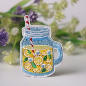 Könnte beinhalten: Gestickter Bügel-Patch mit einem Einmachglas, gefüllt mit Limonade, Zitronen und Eis. Das Glas hat einen rot-weiß gestreiften Strohhalm.
