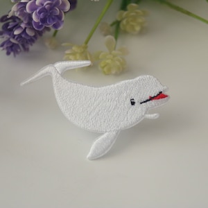 May include: White embroidered iron-on patch of a smiling beluga whale with a red mouth.