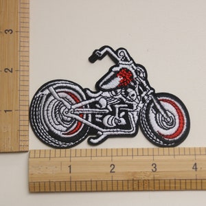 May include: White and red embroidered motorcycle patch. The motorcycle is a chopper style with a skull design on the gas tank.