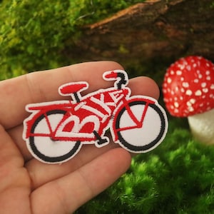 K&ouml;nnte beinhalten: Roter und wei&szlig;er gestickter B&uuml;gelaufkleber mit einem Fahrrad, auf dem das Wort "BIKE" auf dem Rahmen steht.