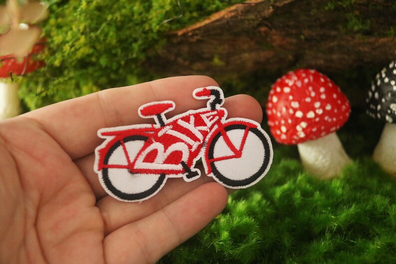 K&ouml;nnte beinhalten: Roter und wei&szlig;er gestickter B&uuml;gelaufkleber mit einem Fahrrad, auf dem das Wort "BIKE" auf dem Rahmen steht.
