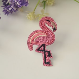 May include: Pink glitter flamingo iron-on patch with black outline.