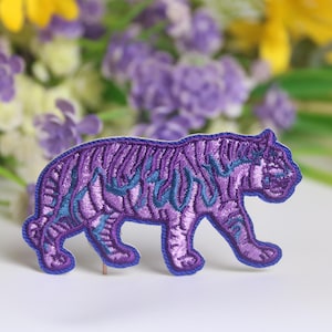 Può includere: Toppa ricamata viola di una tigre con strisce blu.