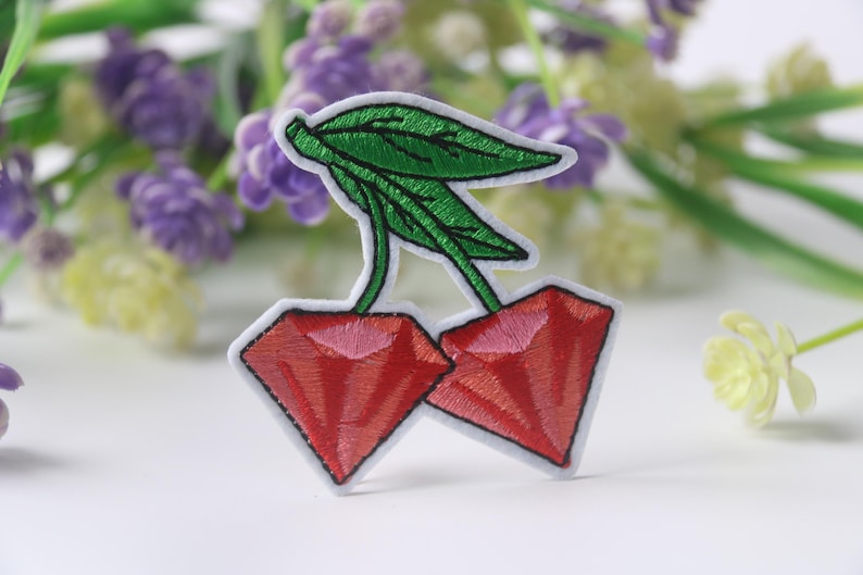 May include: Embroidered iron-on patch of two red cherries with green stems and leaves.
