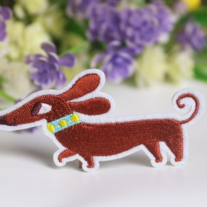 May include: An embroidered dachshund patch in brown with a yellow and blue collar. The dachshund is walking with its tail curled up.