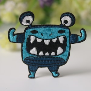 May include: Blue embroidered iron-on patch of a cartoon monster with big teeth, white eyes, and flexing biceps.