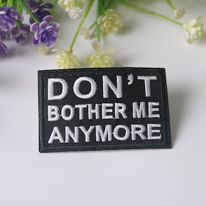 May include: Black embroidered patch with white text that reads "DON'T BOTHER ME ANYMORE".