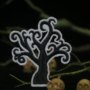 May include: Black and white embroidered patch of a spooky tree with twisting branches. The tree is outlined in white and filled in with black.