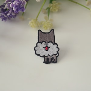 May include: Embroidered iron-on patch of a gray cat with a fluffy white beard. The cat has a red nose and black eyes.