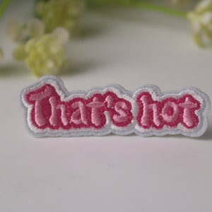 May include: Pink and white embroidered iron-on patch with the text "That's hot" in a cursive font.