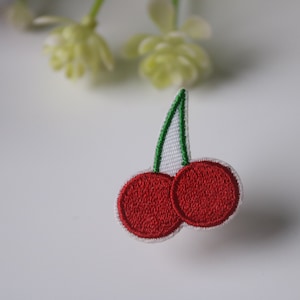 Puede incluir: Parche de cerezas bordadas. Dos cerezas rojas con contornos blancos y un tallo verde. El parche tiene un patrón de puntada detallado, ideal para añadir un toque afrutado a la ropa o accesorios. Aproximadamente 3 cm de ancho.