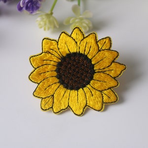 以下が含まれることがあります： 茶色の芯を持つ黄色い刺繍のひまわりパッチ。パッチは、衣服、バッグ、その他のクラフトに自然のタッチを加えるのに最適です。