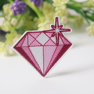 May include: Pink diamond shaped embroidered patch with a white starburst design.