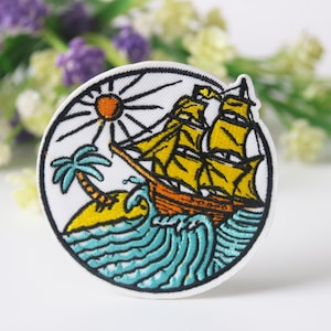 May include: A round embroidered patch with a white background featuring a yellow sailboat with brown sails, a palm tree, and a yellow sun with orange rays. The sailboat is sailing on blue waves.