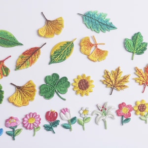 May include: Embroidered patches of various leaves and flowers in vibrant colors. Includes green, yellow, orange, and red leaves, a four-leaf clover, a sunflower, and several flower patches.