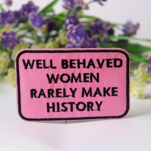 May include: Pink fabric patch with black embroidered text that reads "Well Behaved Women Rarely Make History".