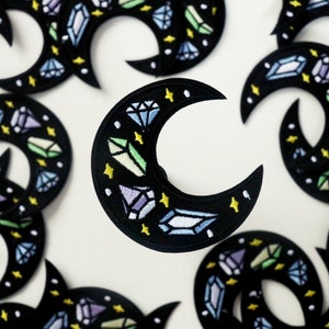 May include: A set of black crescent moon patches with embroidered colourful gemstones and yellow stars.