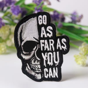 May include: Black and white embroidered patch with a skull design and the text "Go as far as you can".