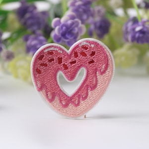Puede incluir: Parche bordado en forma de corazón rosa con un diseño de glaseado rosa y blanco.