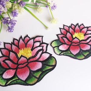May include: Two embroidered iron-on patches of pink water lilies with yellow centers and green leaves.
