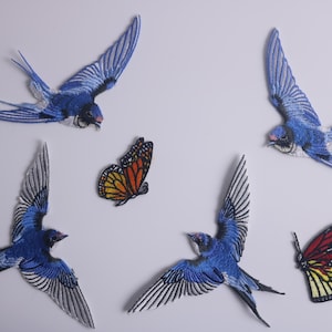 May include: Five embroidered patches featuring blue swallows and butterflies. Two of the butterflies are orange and black, and one is red and orange.