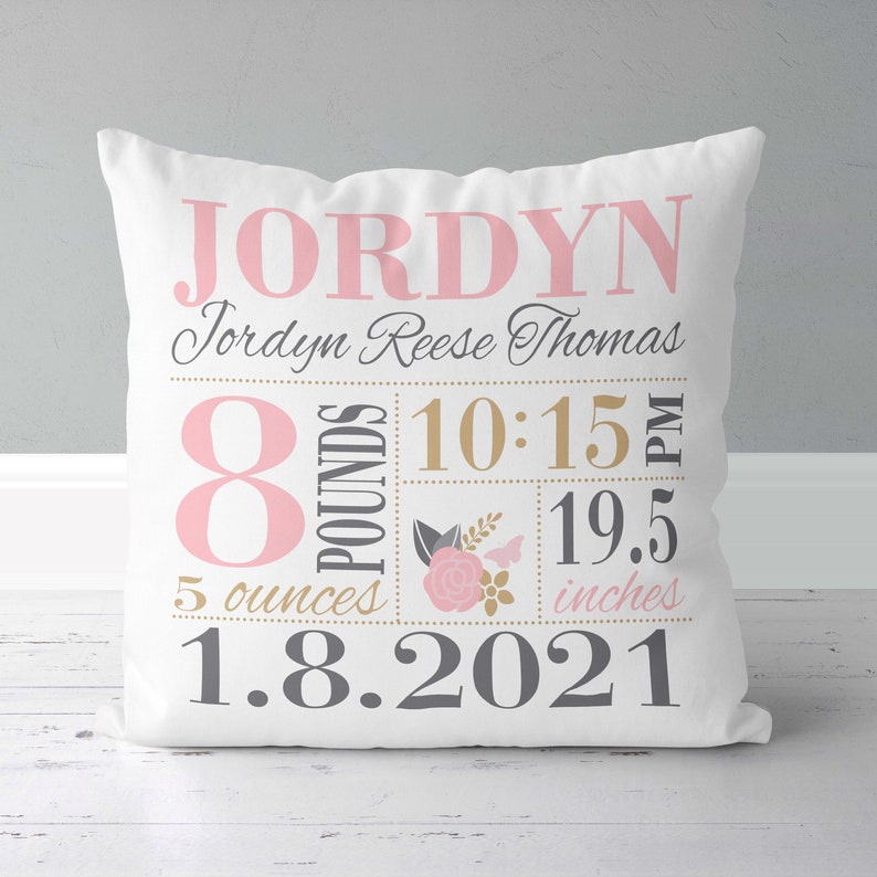 May include: White pillow with pink and gold lettering. The pillow reads "Jordyn Jordyn Reese Thomas 8 pounds 5 ounces 10:15 PM 19.5 inches 1.8.2021".