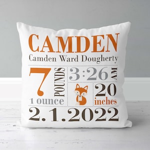 May include: White pillow with a fox design and the text "CAMDEN" in orange. The pillow also includes the text "Camden Ward Dougherty", "7 pounds 1 ounce", "3:26 AM", "20 inches", and "2.1.2022".