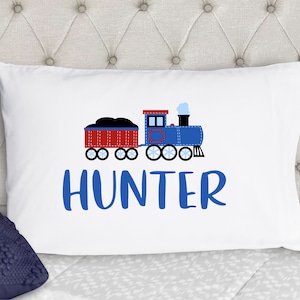 May include: White pillowcase with a blue train and red boxcar with black coal. The train has a white puff of smoke and the text "HUNTER" is below the train.