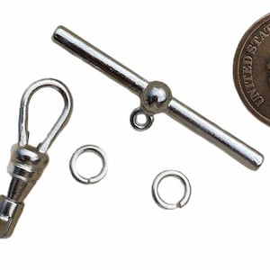 May include: Silver watch chain with a swivel bar, a spring ring, and a T-bar. The chain is made of polished metal and has a classic design.