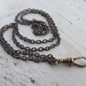 May include: A brown chain with a gold-toned clasp. The chain is made of linked circles and is about 18 inches long.