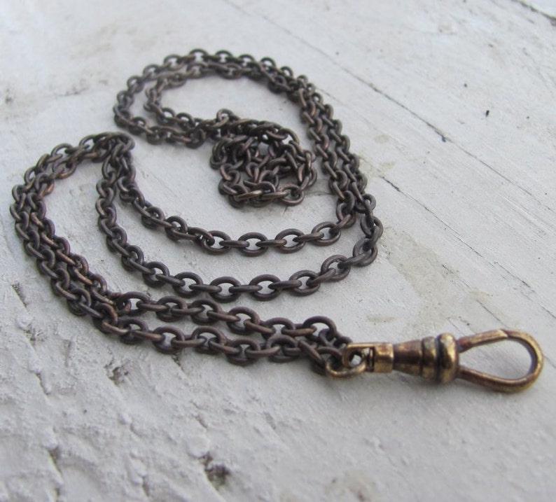 May include: A brown chain with a gold-toned clasp. The chain is made of linked circles and is about 18 inches long.