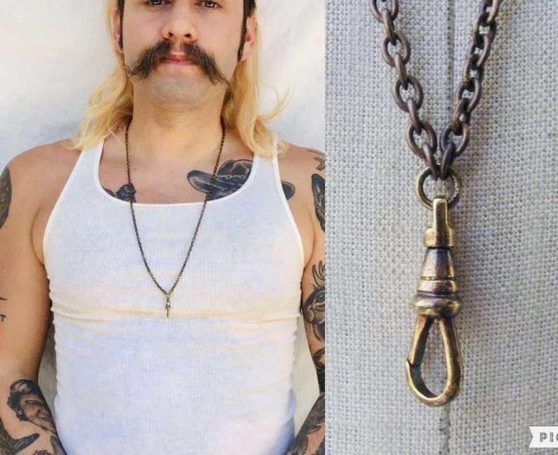 May include: A close-up of a brass chain necklace with a hook clasp. The chain is thick and has a vintage look. The necklace is worn by a person with a white tank top.