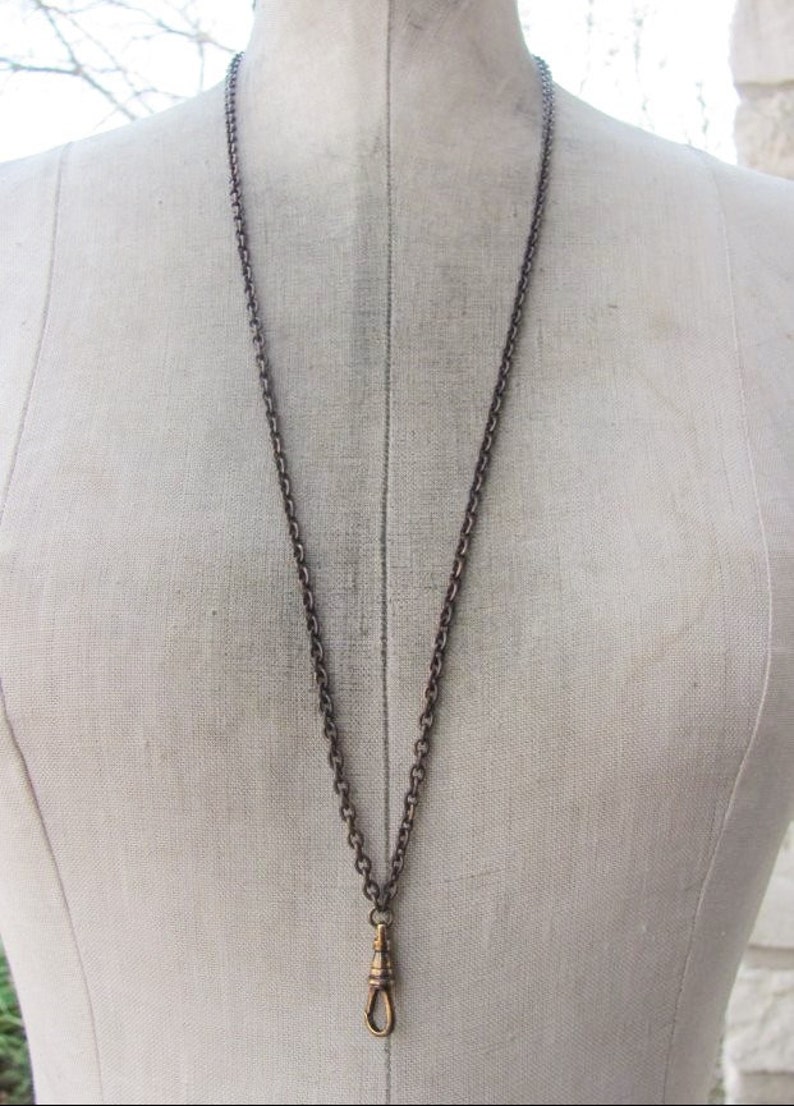 May include: A silver chain necklace with a gold-toned clasp. The chain is a simple, linked design.