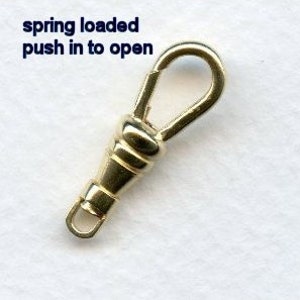 May include: Gold-toned spring-loaded clasp with a small loop on one end and a larger loop on the other. The text "spring loaded push in to open" is written above the clasp.