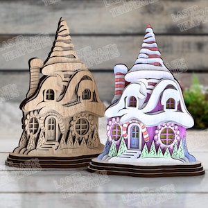May include: Two wooden laser-cut decorative houses. One is natural wood, the other is painted pink, white, and red. Both have detailed windows, doors, and chimneys. The houses are designed with a whimsical, fairytale aesthetic.