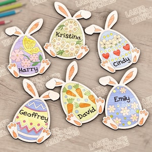 Può includere: Ornamenti a forma di uova di Pasqua in legno a forma di coniglietti. Ogni uovo è decorato con disegni colorati, tra cui fiori, farfalle e carote, e personalizzato con nomi come Harry, Kristina e Cindy. Perfetto per Pasqua.