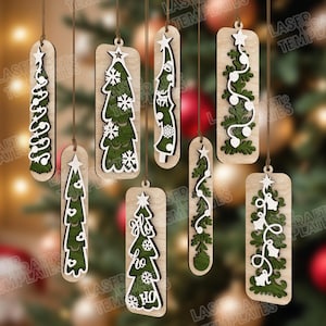 May include: A collection of wooden Christmas tree ornaments. Each ornament features a unique design, including tree shapes, snowflakes, and the text "Ho Ho Ho". The ornaments are suspended by brown strings against a blurred background.