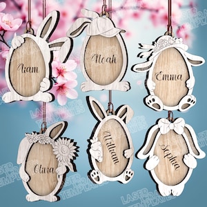 May include: Wooden Easter egg ornaments with bunny ears and names Liam, Noah, Emma, Olivia, William, and Sophia. Each ornament is laser cut with a unique bunny design and a wooden egg-shaped center.