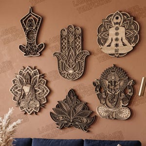 Peut inclure: Un ensemble de six décorations murales en bois superposé avec des motifs complexes découpés au laser. Le lot comprend une silhouette de yoga, une main de hamsa, une figure méditative avec des chakras, un Bouddha, un lotus et un Ganesha.