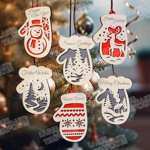 Op de afbeelding: Een verzameling houten kerstversieringen in de vorm van wanten. Elke versiering heeft een uniek ontwerp, waaronder een sneeuwpop, rendieren en bomen. De ornamenten hebben feestelijke teksten zoals "Gelukkig Nieuwjaar" en "Vrolijk Kerstfeest".