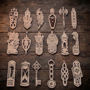 Op de afbeelding: Een verzameling van zeventien lasergesneden houten bladwijzers met ingewikkelde fantasieontwerpen, waaronder een schild, kristal, veer, toverdrankflesje, bijl, runen, draak, toren, zandloper, sleutel, kompas en boeken met diverse inscripties.
