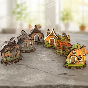 May include: A collection of laser-cut wooden fairy houses in various designs. The houses feature details like arched doorways, chimneys, and pumpkin-shaped structures, with green and orange color schemes. The bases are detailed with grass.