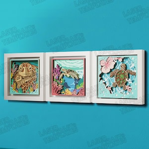 May include: Three framed, layered art pieces depicting sea turtles in underwater scenes. Each artwork features intricate laser-cut designs of turtles, coral, and aquatic plants. The white frames are mounted on a blue wall.