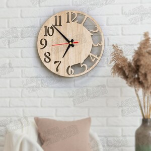Puede incluir: Un reloj de pared redondo de madera con n&uacute;meros recortados y un dise&ntilde;o parcialmente abierto. El reloj tiene manecillas negras y un segundero rojo. El reloj est&aacute; montado en una pared de ladrillo blanco.