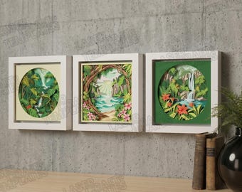 Könnte beinhalten: Drei gerahmte Papierkunstwerke, die tropische Szenen mit Wasserfällen und üppigem Grün darstellen. Die Kunstwerke sind in weißen Rahmen gefasst und an einer grauen Betonwand angebracht. Die Stücke werden über einem Holzregal ausgestellt.