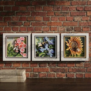 Può includere: Tre opere d'arte floreali incorniciate. La prima presenta fiori rosa e un'ape, la seconda fiori blu e un'ape, e la terza un girasole e un'ape. Il tutto è ambientato su un muro di mattoni.