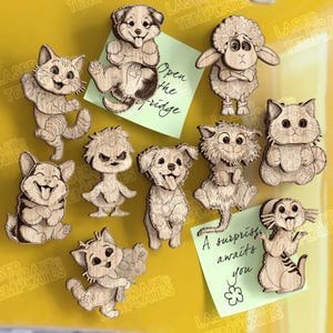 May include: A selection of wooden animal magnets, featuring cats, dogs, and a sheep, with engraved details. Some magnets are holding objects or have their tongues out. Two sticky notes read "Open the fridge" and "A surprise awaits you."