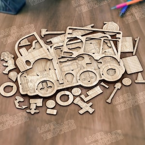 Pode incluir: Um quebra-cabeça de madeira de um caminhão de bombeiros com várias peças recortadas, incluindo um bombeiro, ferramentas e um cone de trânsito. As peças estão dispostas em uma superfície marrom, prontas para montagem.