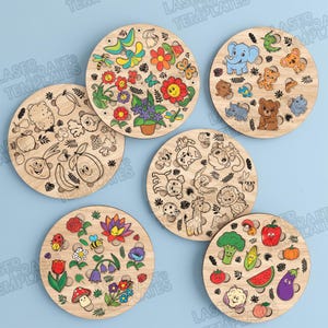Peut inclure: Cinq planches circulaires en bois présentant des motifs découpés au laser sur divers thèmes, notamment des fleurs colorées, des animaux de dessin animé, ainsi que des fruits et légumes souriants, avec des découpes circulaires.